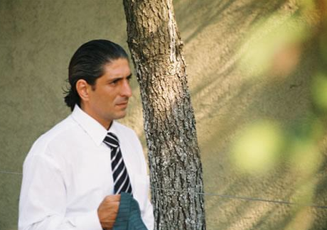 Erkan Aydoğan Oflu mit Pferdezopf im weissen Hemd mit gestreifter Krawatte.