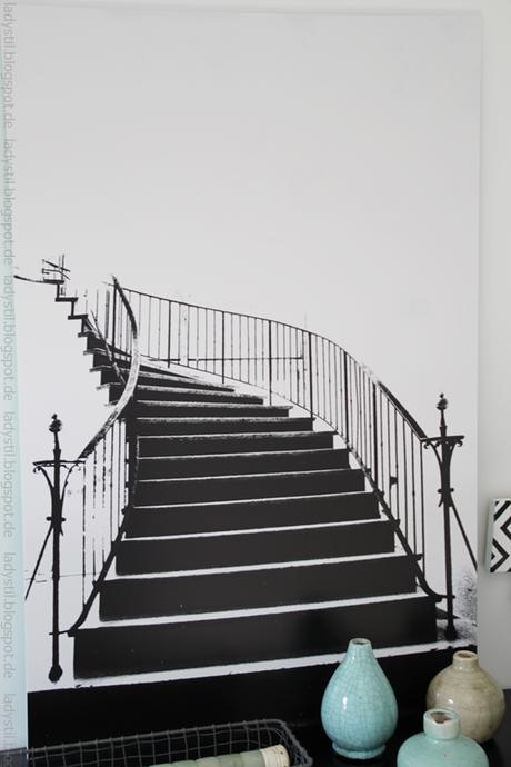 Poster einer schwarzen Wendeltreppe auf weißem Grund hängt über einer schwarzen Kommode