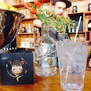 Gin and Tonic, Clockers Heft, Ginflasche als Blumenvase und der Barkeeper im Hintergrund