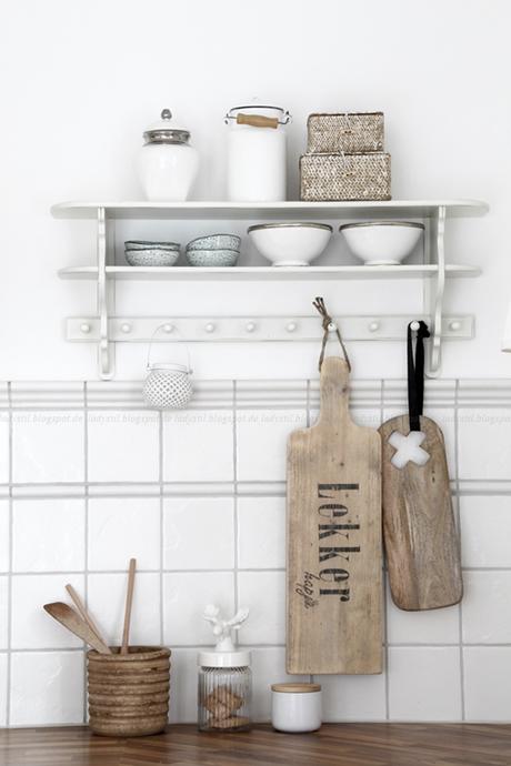 Küchenregal in weiß mit weißen Accessoires, es hängen große Holzbrettchen daran