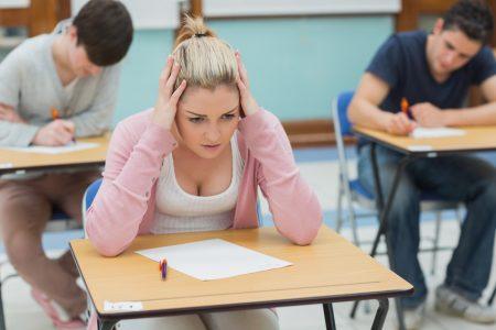 Stressed student sitting at a desk in a classroom and having an examination