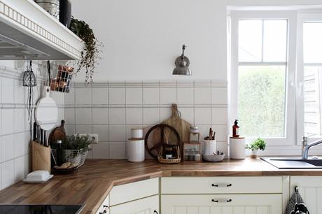 Kücheneinrichtung in Schwarz Weiß Holz mit leichten New Boho Elementen, holzfarbene Arbeitsplatte mit weißen Accessoires, House Doctor Gefäß