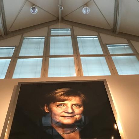 Wie in der DDR: Angela Merkel,  Schutzpatronin und Staatsikone der Deutschen wacht über der Ausstellung
