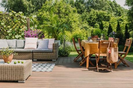 Premium Gartenmöbel – Ein umfassender Ratgeber Gartenmöbel auf einer Terrasse, Sitzlandschaft aus Rattanmöbeln mit einer Sofa Lounge und einem Holz Esstisch inmitten der grünen Natur