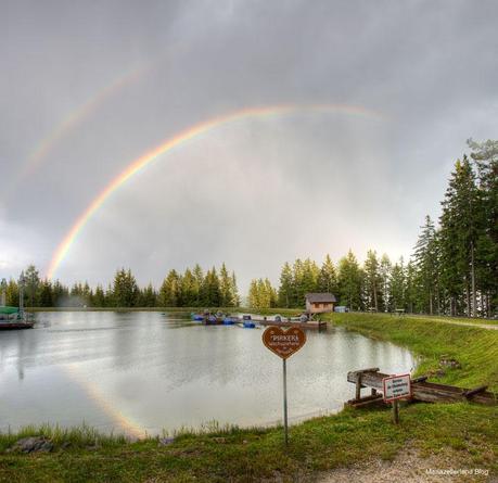 Bergwelle mit Regenbogen Spiegelung im See