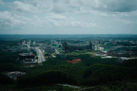 Nusantara 2025: Unsere Reise in Indonesiens neue Hauptstadt Luftaufnahme der weitläufigen Landschaft von Nusantara mit modernen Gebäuden, verschlungenen Straßen und üppigem Grün unter einem bewölkten Himmel.