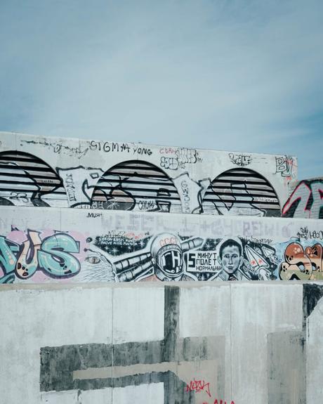 Tallinn: Die 10 besten Sehenswürdigkeiten Eine Betonmauer mit bunten Graffiti und Wandmalereien erhellt die Straßen von Tallinn unter einem blauen Himmel.