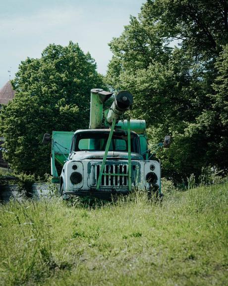 Tallinn: Die 10 besten Sehenswürdigkeiten Altes, verwittertes Militärfahrzeug mit einer Kanone, geparkt im hohen Gras in der Nähe von Tallinn, mit Bäumen im Hintergrund.