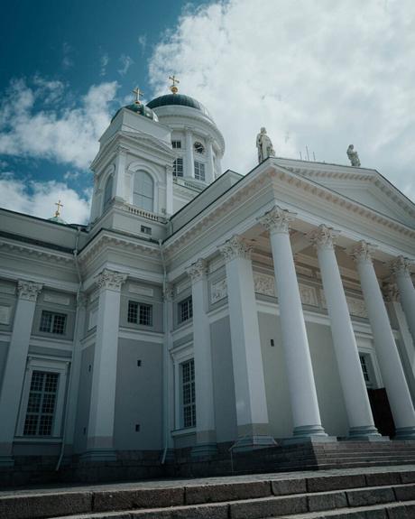 Helsinki: Die 10 besten Sehenswürdigkeiten Weiße neoklassizistische Kathedrale von Helsinki mit hohen Säulen und grünen Kuppeln unter einem teilweise bewölkten Himmel.