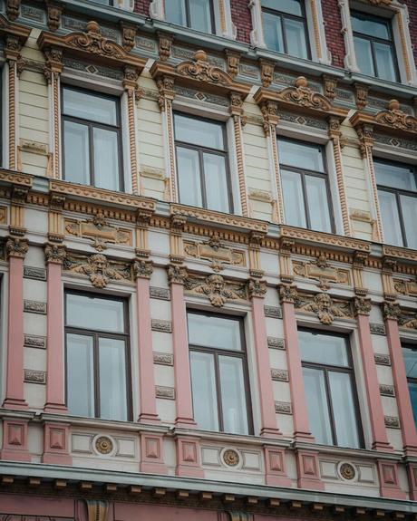 Helsinki: Die 10 besten Sehenswürdigkeiten Verschnörkelte Gebäudefassade in Helsinki mit großen Fenstern, dekorativen Säulen und detaillierten architektonischen Schnitzereien.