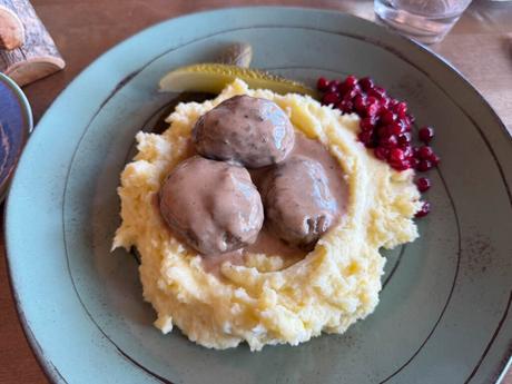 Im Bann des Mitternachtslichts: Ein Abenteuer in Finnisch-Lappland Kartoffelpüree mit drei Fleischbällchen in Bratensoße, garniert mit Preiselbeeren und einer Gurkenscheibe.