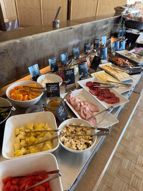 Im Bann des Mitternachtslichts: Ein Abenteuer in Finnisch-Lappland Buffet-Tisch mit verschiedenen Früchten, Aufschnitt, Käse und Gewürzen in Schalen und Tabletts.