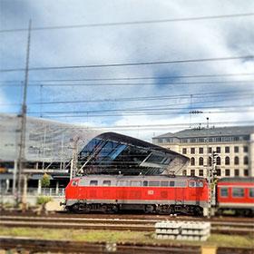 Instagram - München Hackerbrücke mit blau-weißem Himmel - Bahnstation mit rotem Zug