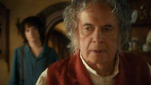 Ian Holm als alter Bilbo Beutlin, im Hintergrund Elijah Wood als Frodo Beutlin