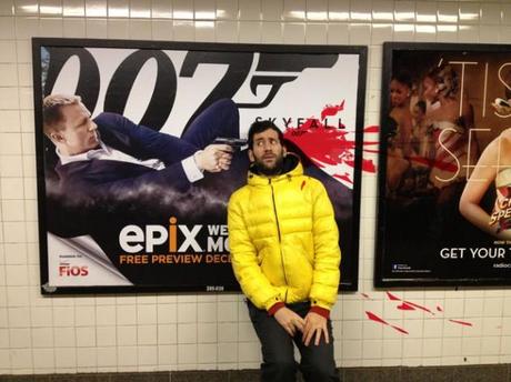 Künstler posiert neben Filmplakaten, um auf die dargestellte Gewalt hinzuweisen
