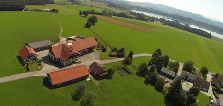 Luftaufnahme unseres Bauernhofes mit dem Grabensee im Hintergrund