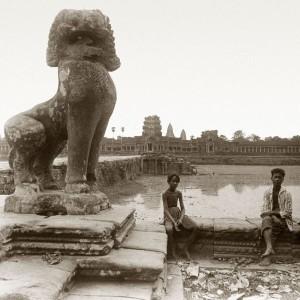 Zwei Jungen sitzen im Vordergrund von Angkor Wat.