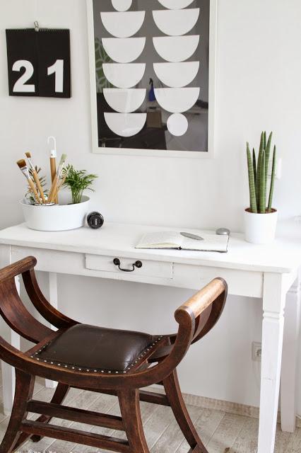 Schreibtisch in Weiß mit antikem braunen Hocker davor Im Hintergrund Blumenampel als Pinselhalter