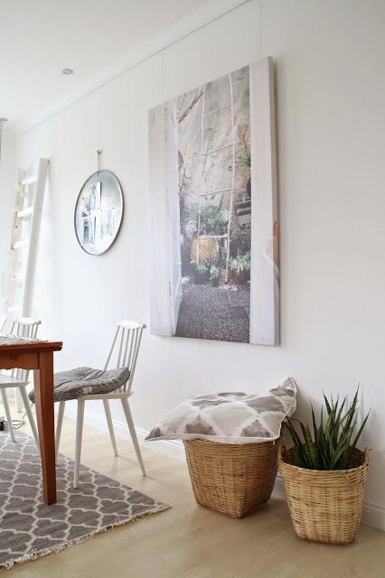 Ansicht der großen Leinwand mit Leitermotiv und vielen Pflanzen sowie Teil des Esszimmertischs mit weißem Stuhl und graugemustertem Teppich