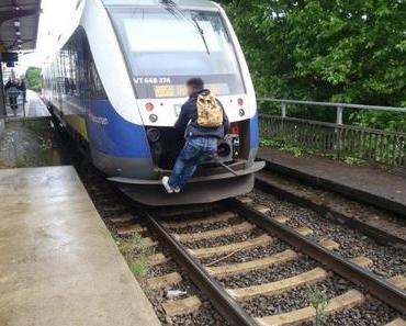 Mann fährt auf der Zugkupplung einer NordWestBahn mit