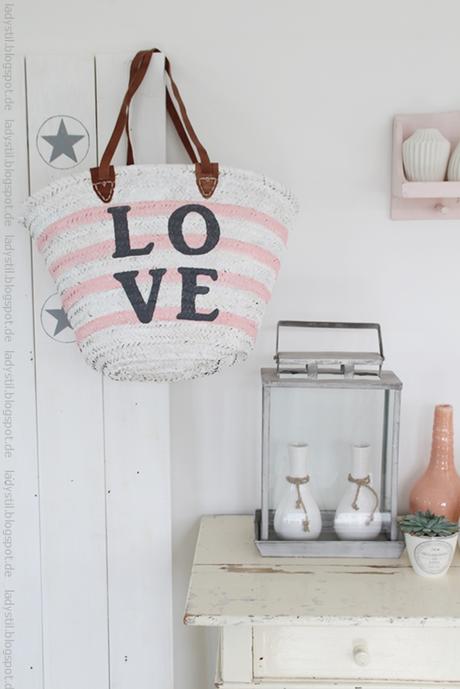 Weiß rosa gestreifte Korbtasche mit großem love Schriftzug hängt an einer Sternentafel rechts davon Kommode mit diversen Wohnaccessoires für den Bloggeroptimierungsfotowettbewerbbeipixum