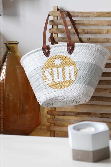 Korbtasche weiß mit goldenem Kreis und weißem sun Schriftzug darin hängt an einer Bambuspinnwand daneben eine große braune Bodenvase für den Bloggeroptimierungsfotowettbewerbbeipixum
