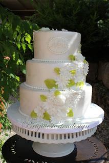 Hochzeitstorte in weiß mit kleinen Blümchen und hellgrünen Blättern