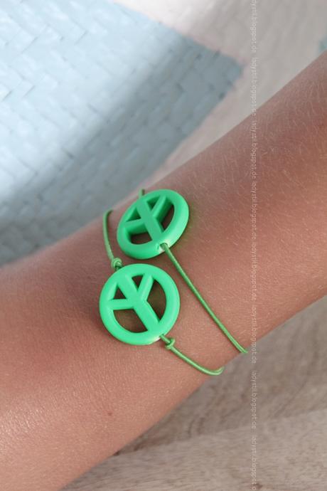 grünes Peace-Armband am Arm 