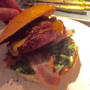 Burger mit Hack-Patty, Bacon, Cheddarkäse, Salat und Karamellzwiebeln