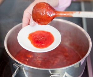 Mit einem sauberen Holzlöffel ein wenig von der Marmelade auf einen Teller oder Schälchen schütten, um zu testen, ob die Marmelade ausreichend geliert.