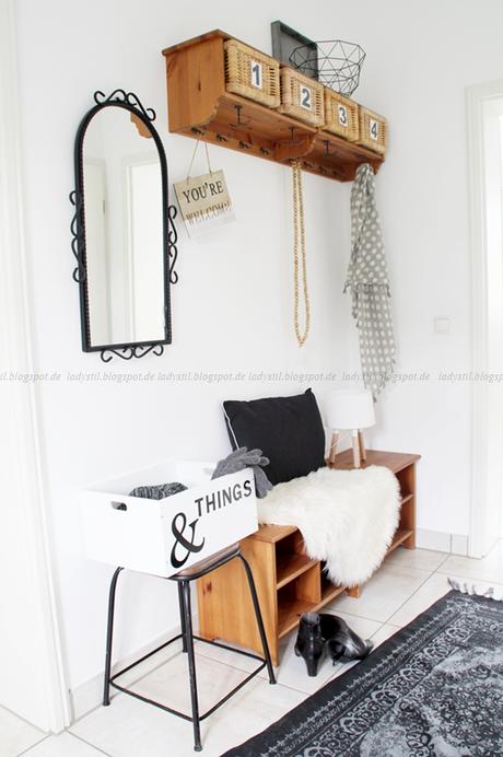 Blick in den Flur mit Garderobe Spiegel und Wohnaccessoires in schwarz weiß Holz als Kombination