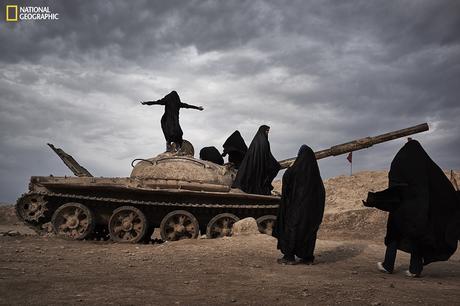 There are relics left along the Iran-Iraq boarders. A group of Iranian female students play around an abandoned tank. Among them, one girl stands on the tank with her arms open. 