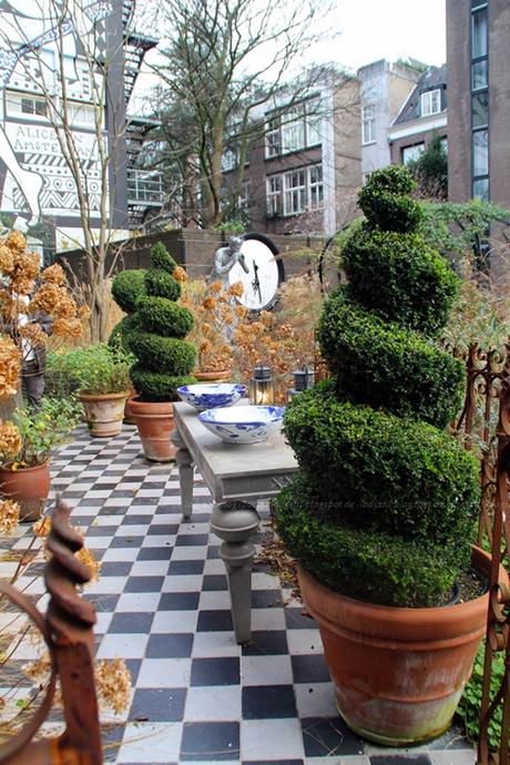 Garten des Hotels Andaz Hyatt Amsterdam mit Mosaikweg und Buchsbaumsäulen sowie dekorativen Elementen