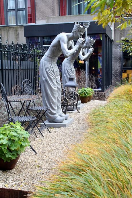 Garten des Hotels Andaz Hyatt Amsterdam mit zwei Skulpturen an einem Kiesweg