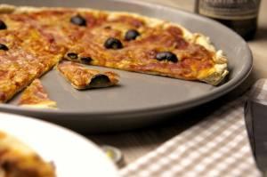Biertreber-Pizza mit Bacon und schwarzen Oliven