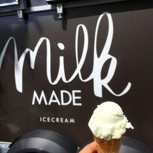 Eiskugel im Hörnchen vor dem Logo von Milk Made Ice Cream