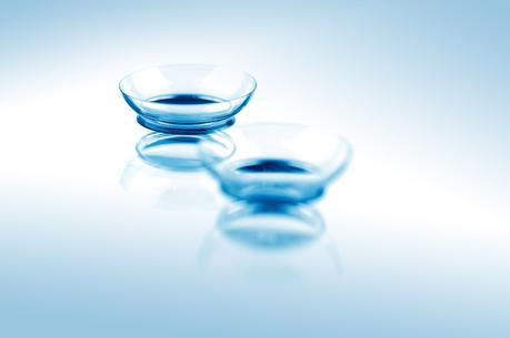 Two contact lenses with reflections on blue surfaces. Focus on long-distance lens. ** Note: Shallow depth of field