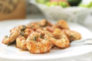 Fried black tiger prawns with herbs and spices on a white plate.