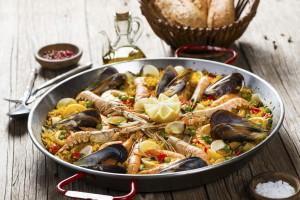 Closeup of paella with seafood on a wooden table, selective focus.
