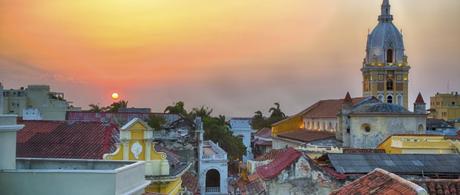 View over the rooftops of the old city of Cartagena during a vibrant sunset. The spire of Cartagena Cathedral stands tall and proud.