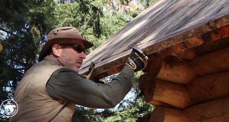 Handwerker baut sich mit einfachen Werkzeugen eine Holzhütte