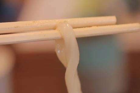 Udon Nudeln mit Stäbchen essen ist nur mit viel Übung zu bewältigen.