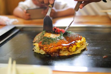 Okonomiyaki werden zum Essen in mundgerechte Stücke zerteilt.