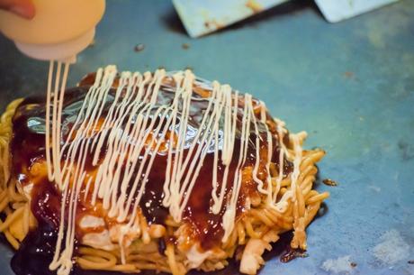 Okonomiyaki werden mit japanischer Mayonnaise im Zickzack garniert.