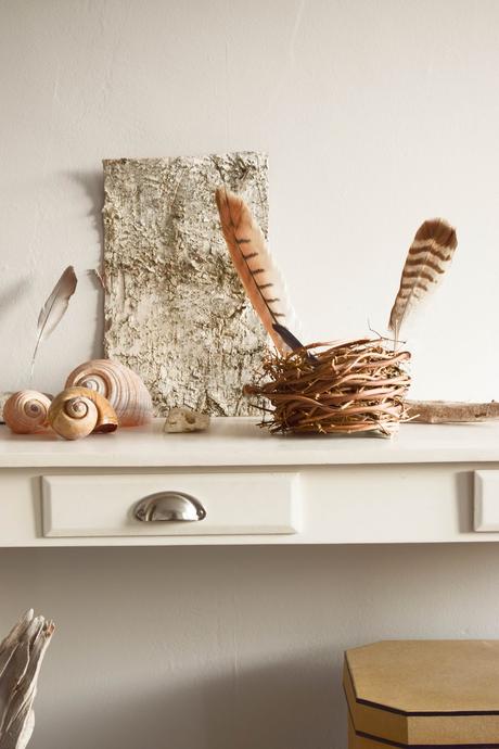 Sideboard Deko weiß mit natürlichen Materialien: Federn, Schneckenhaus und Holz. Dekoidee mit Natur.