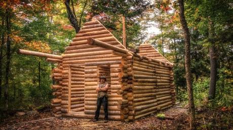 Nur ein Mann, der sich alleine eine Blockhütte im Wald baut