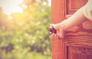 Den Anfang schreiben: Frauenhand öffnet eine Tür, hinter der sich ein Garten zeigt
