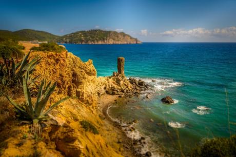 Wassertemperatur Ibiza: Isoliert stehende Felsnadel vor einer Steilküste mit türkis-blauem Mittelmeer