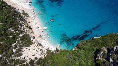 Wassertemperatur Cala Millor: Helle Kalksteinbucht mit türkis-blauem Meer von oben, umrahmt von saftig grünen Baumkronen