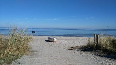 Wassertemperatur Scharbeutz: Sandstrand mit tiefblauem Meer, Dünengras und Boot